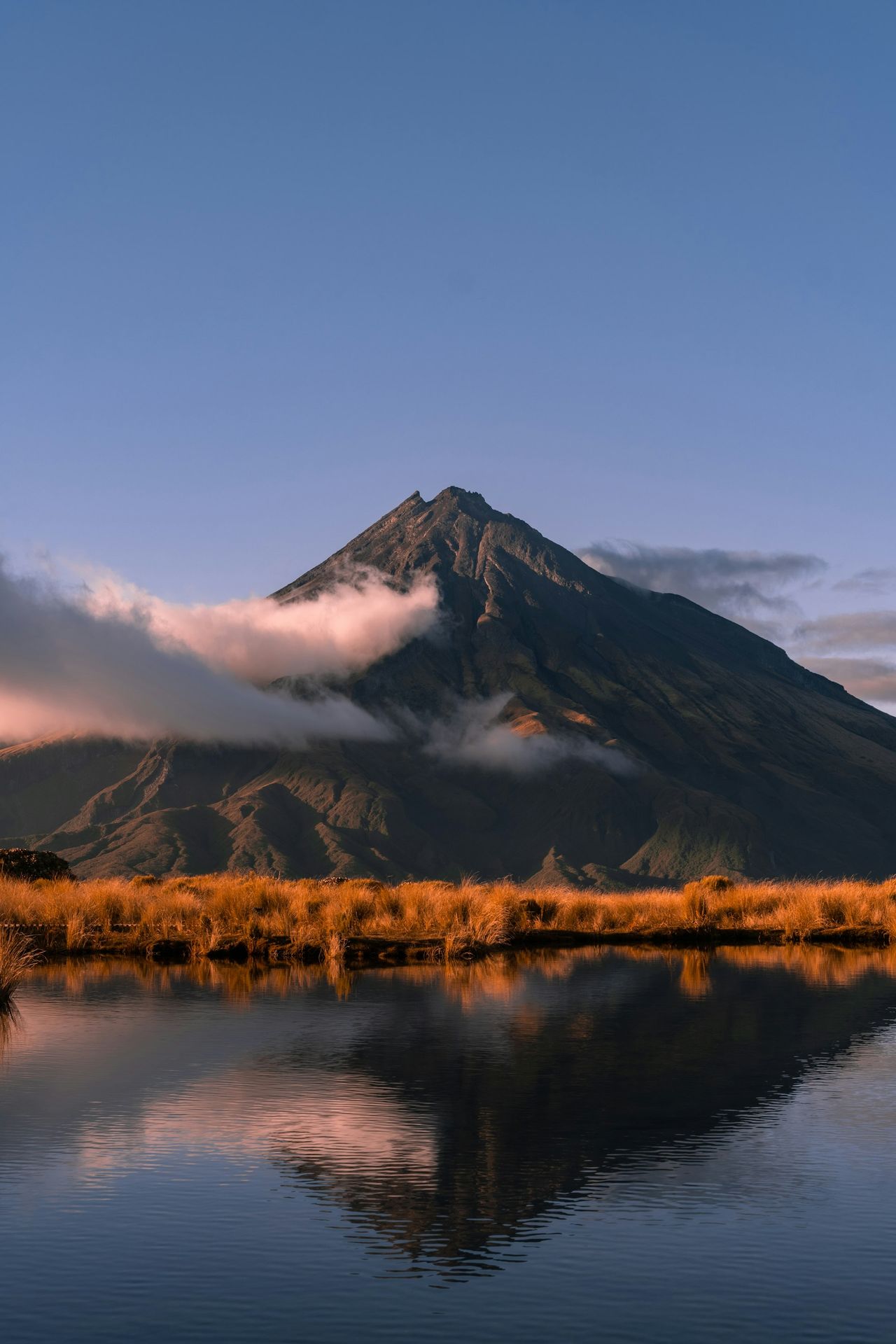 brown grass field near mountain under white clouds during daytime